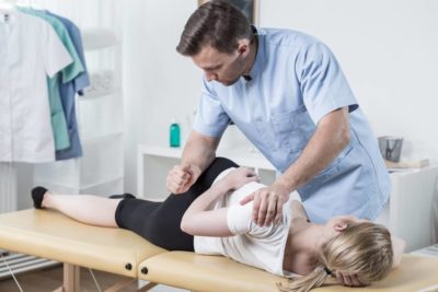 chiropractor adjusting female patients lower back