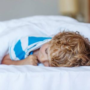 young boy sleeping in his bed